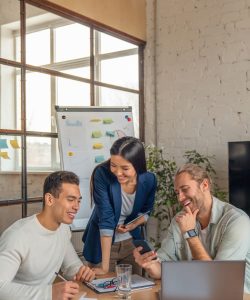 Vertical shot of multiracial business people with laptop and smartphone having meeting in office.